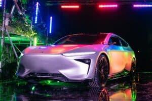 Un Liux Animal, un coche moderno con un diseño elegante, con líneas dinámicas y una forma aerodinámica, iluminado con luces coloridas que se reflejan en su superficie, creando una apariencia vibrante y futurista.