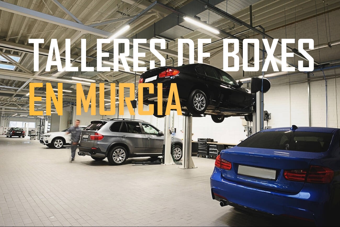 Imagen de un taller de automóviles en Murcia, donde cambiar el aceite del coche uno mismo en Murcia. Se ven varios coches, incluyendo un coche negro elevado en un elevador y un coche azul en primer plano. Un mecánico está caminando por el taller, que tiene un suelo de baldosas y una iluminación brillante. El texto en la imagen dice "TALLERES DE BOXES EN MURCIA".