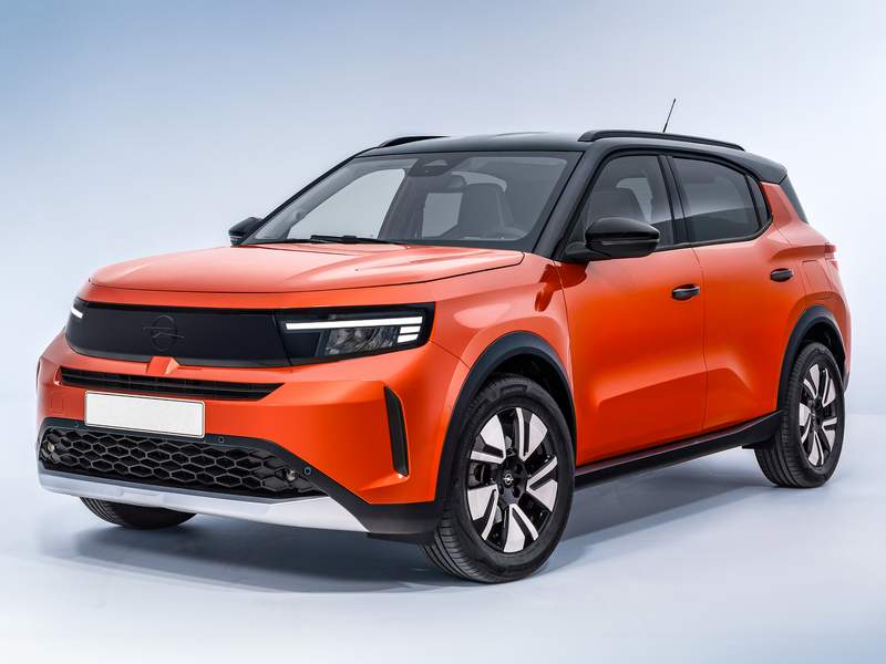 Imagen de un modelo nuevo del Opel Frontera, un SUV compacto. El vehículo está pintado en un color naranja brillante con detalles en negro, incluyendo el techo, los espejos laterales y la parte inferior del parachoques delantero. El diseño frontal presenta un aspecto elegante y moderno con una parrilla negra y faros LED integrados. El coche tiene una apariencia deportiva y robusta, con grandes ruedas de aleación y una alta distancia al suelo, lo que lo hace adecuado tanto para la conducción urbana como para el todoterreno. Esta imagen es interesante y relevante ya que muestra el último diseño y características del nuevo Frontera, destacando su estética moderna y su potencial atractivo para los consumidores que buscan un SUV estilizado y versátil.