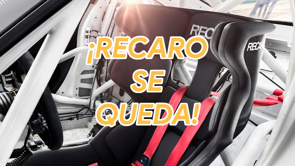 La imagen muestra el interior de un coche de carreras, centrado en un asiento de carreras RECARO. El asiento es negro con arneses rojos y lleva el logotipo de RECARO de manera prominente. El texto superpuesto en la imagen dice "¡RECARO SE QUEDA!", lo que sugiere que los asientos RECARO seguirán siendo utilizados, posiblemente en un equipo de carreras específico o en un modelo de vehículo. Esta imagen es interesante y relevante porque destaca la importancia de equipos especializados de alta calidad en el automovilismo para la seguridad y el rendimiento.