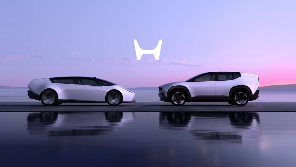 Imagen de dos automóviles futuristas posicionados uno al lado del otro frente a un fondo sereno de un cuerpo de agua y un cielo de colores pastel. A la izquierda, un Honda 0 Saloon de perfil, con un diseño aerodinámico y moderno. A la derecha, un SUV más robusto y alto. Ambos vehículos tienen un diseño angular y minimalista con grandes ruedas. El reflejo de los coches y el logotipo estilizado que parece una 'H' se pueden ver en el agua, añadiendo atractivo visual a la imagen.